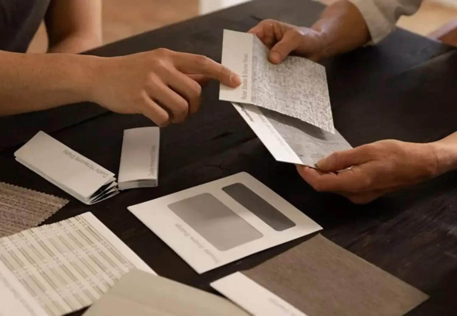 in home design consultation where salesperson showing fabric samples of window shades to homeowner